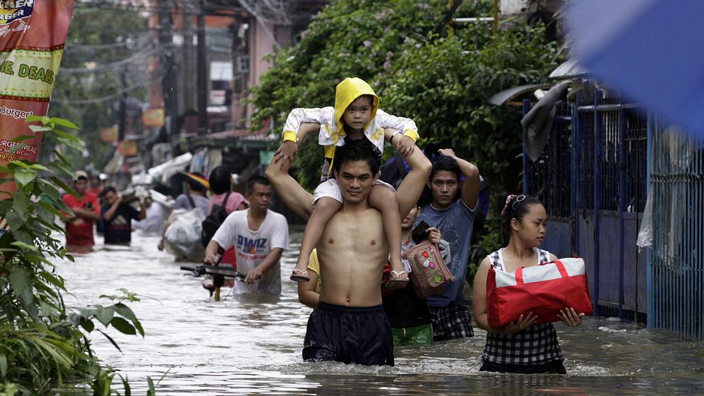 Familjer lämnar sina hem för att söka skydd på högre höjd undan översvämningarna i Pasig City, en förort till Filippinska huvudstaden Manilla.
