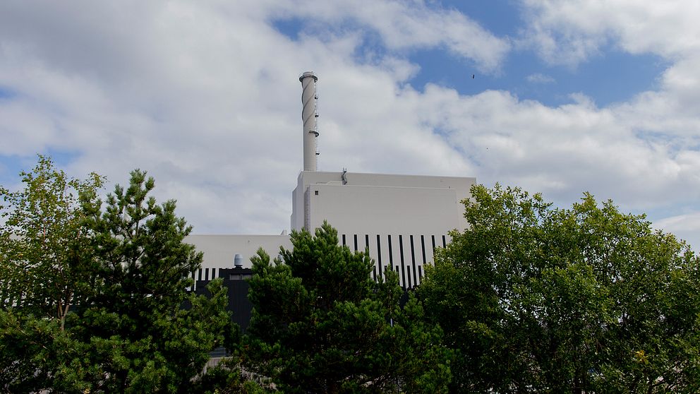 Kärnkraftverket O3 med träd i förgrunden och molnig himmel i bakgrunden.