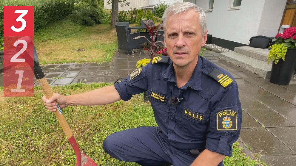 Polisen Henrik Blusi sitter på huk och håller i en hink och spade.