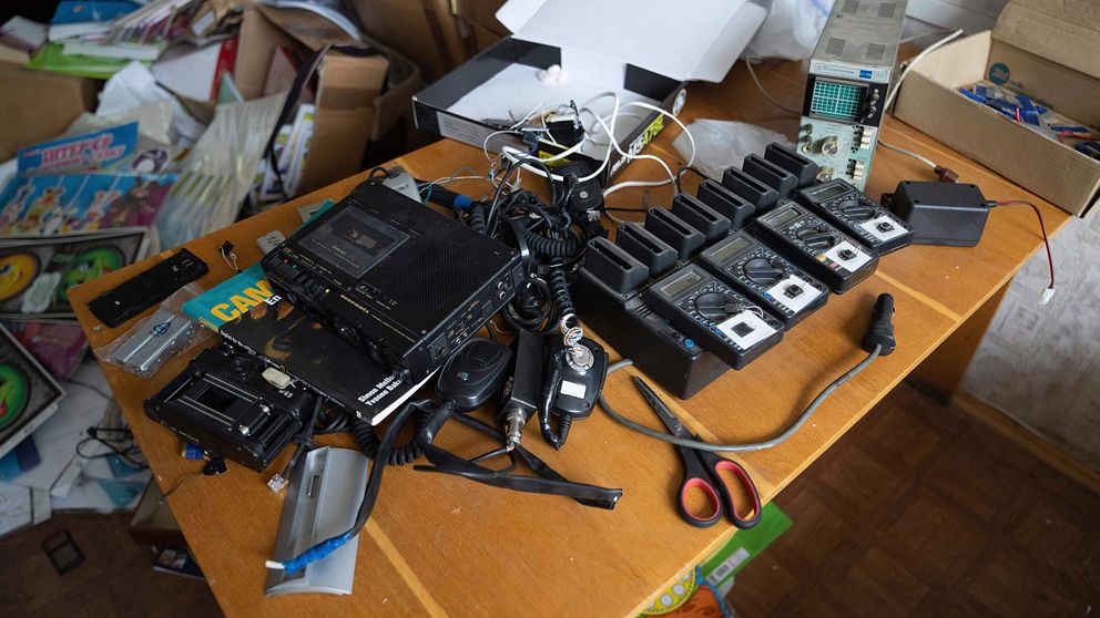 Elektronisk utrustning på ett gammalt teakbord, vid sidan av papper och tidningar