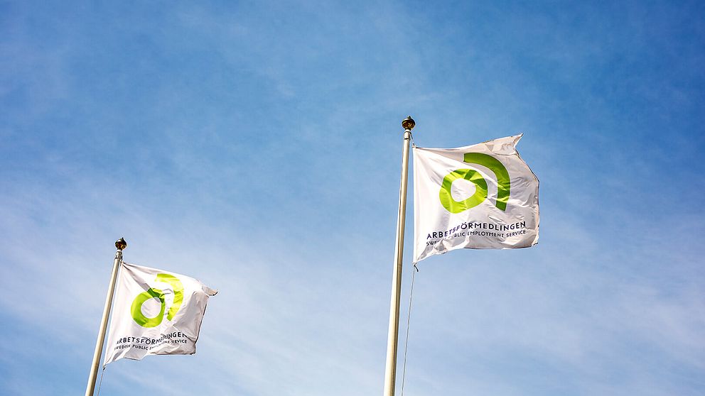 Två Flaggor med arbetsförmedlingens logotyper på.