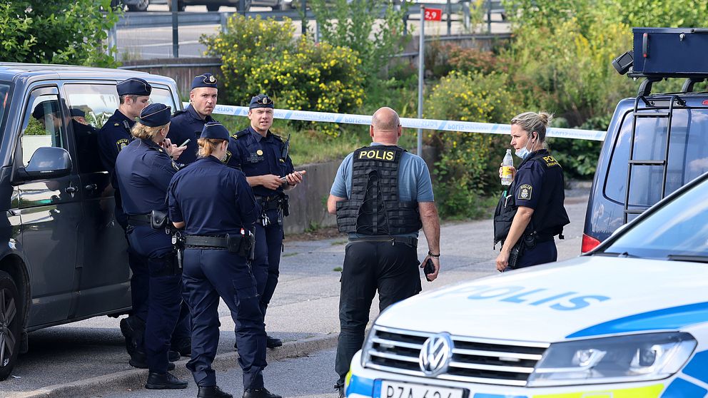 En grupp poliser bakom en avspärrning