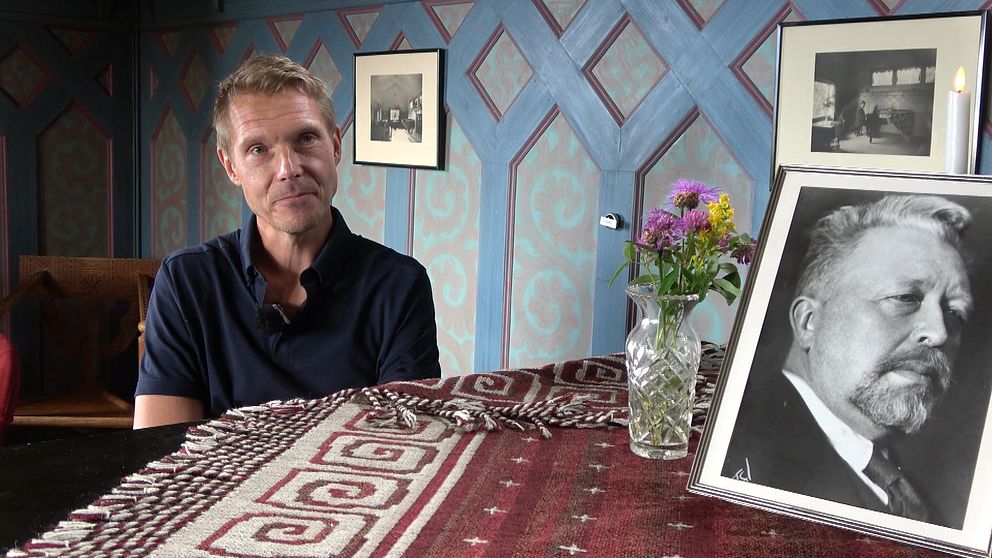 I stora salen i villa Sommarhagen, vid pianot sitter kompositören Mika Pelo. I förgrunden en bild på Peterson-Berger. Mika Pelo har en pikétröja och på pianot finns även en kristallvas med sommarblomster.