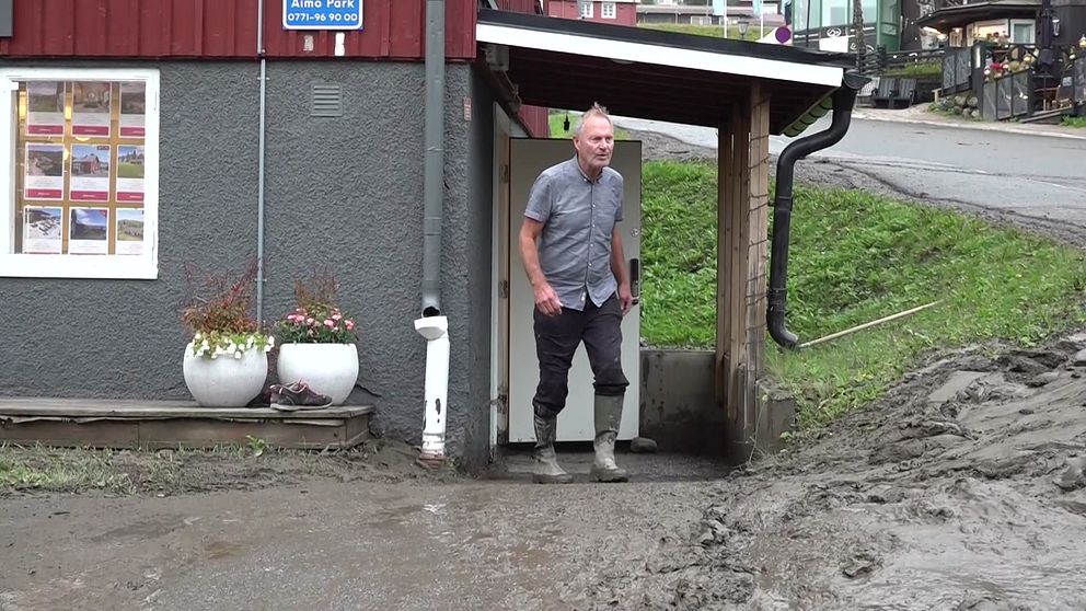 En företagare utanför sin lokal i centrala Åre där marken är lerig av översvämningen i Susabäcken.