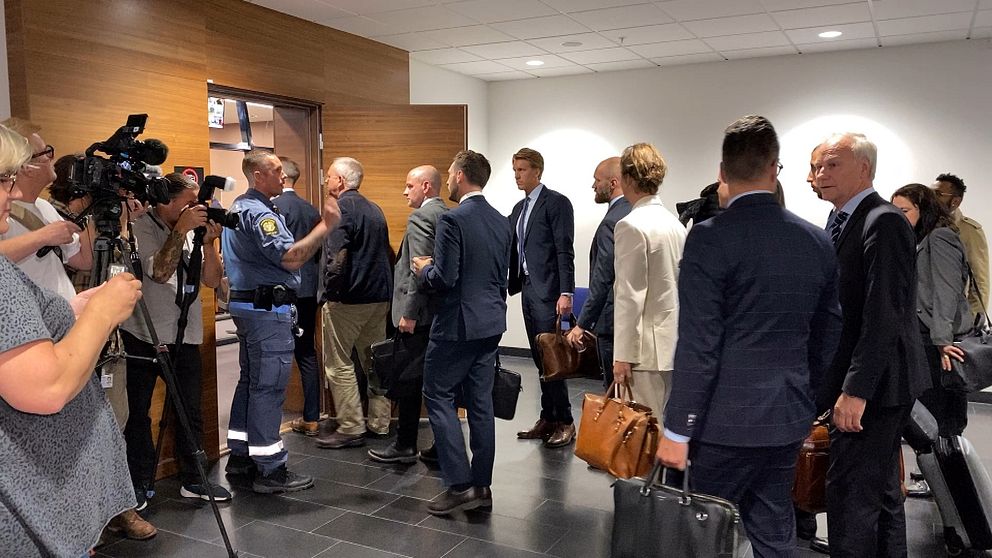 En stor mängs press, advokater och andra kostymkläddda män och kvinnor släpps in i tingsrättssalen.
