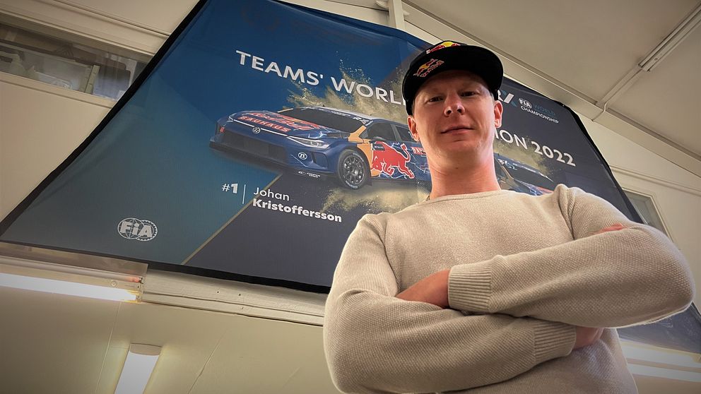 Rallycrossföraren och regerande världsmästaren Johan Kristoffersson står framför en plansch med sin tävlingsbil.