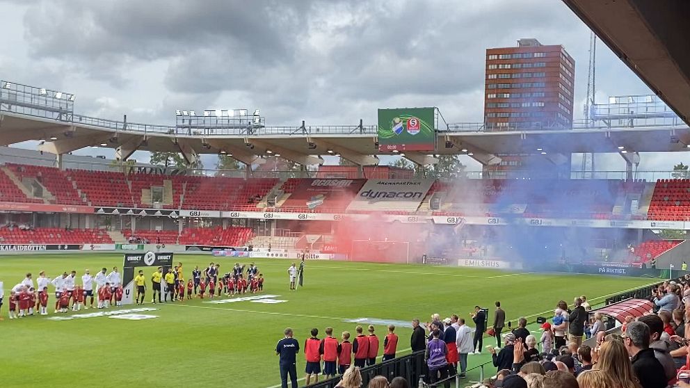 Röd och blå rök från pyroteknik på läktaren.