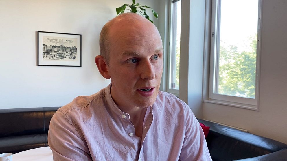 Ledarskribenten Jonas Bergström sitter iklädd rosa skjorta i en soffa på Tidningen Ångermanlands redaktion.