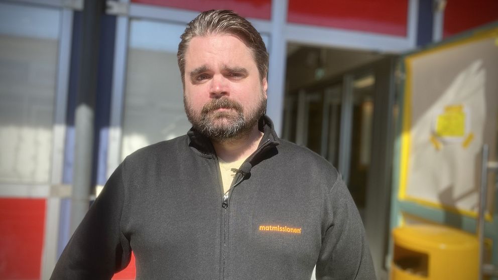 En man i svart tröja och skägg ser allvarlig ut