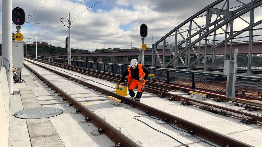 En man utför tekniska mätningar vid rälsen på den nybyggda bron.