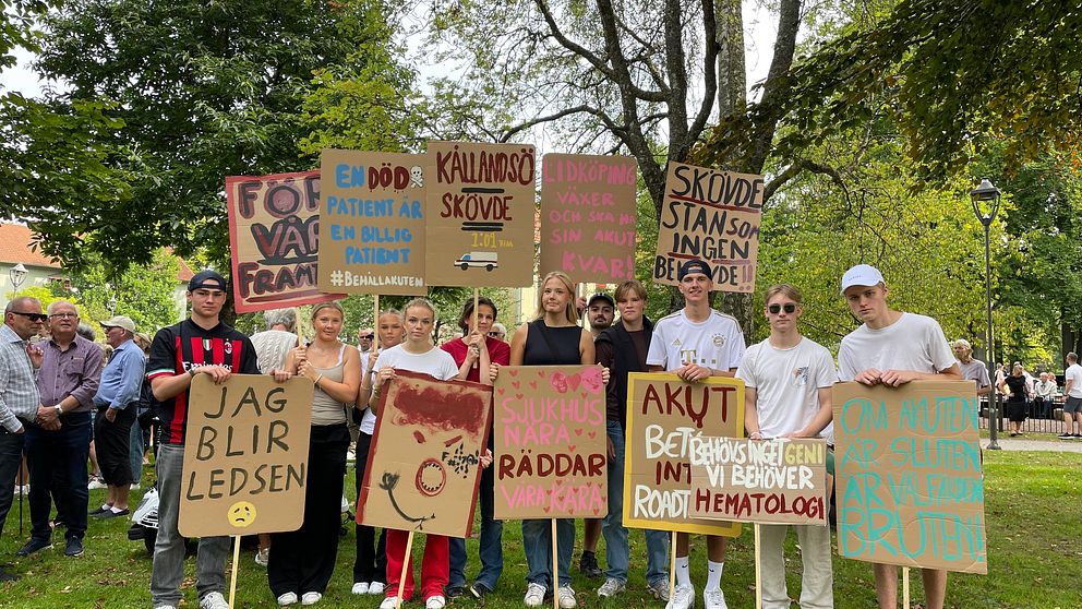 Foto på ett tio-tal unga demonstranter i Lidköping, hållandes i stora plakat med texter i protest mot nedläggningen av akuten i staden.