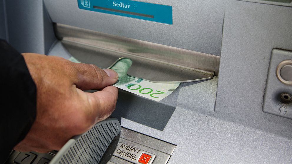 Hand som tar ut pengar ur en bankomat.