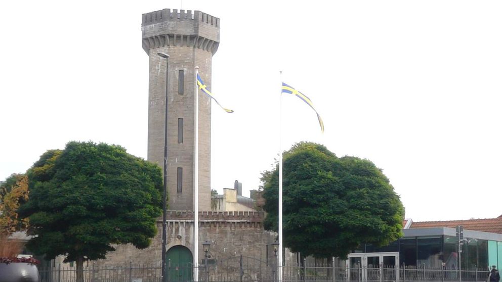 Vattenborgen, Karlskrona, grått torn mot ljus himmel, två gröna träd, två fläggstänger med vimplar.