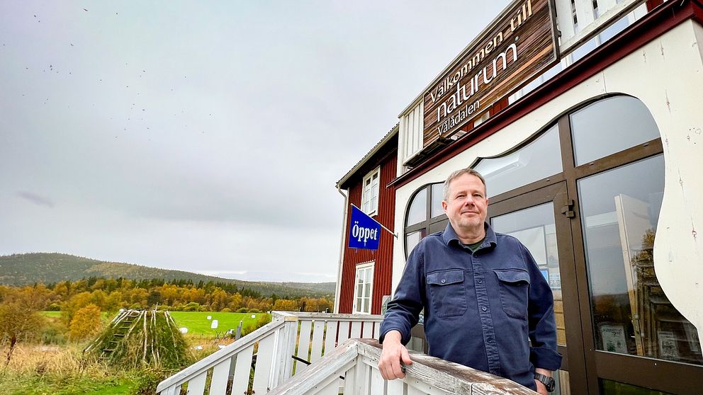 Ola Fransson står på trappan utanför Naturum i Vålådalen med ett landskap i höstskrud i bakgrunden.