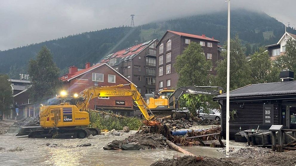 Åre by. Översvämning vatten och en grävmaskin i förgrunden. Åreskutan i bakgrunden.