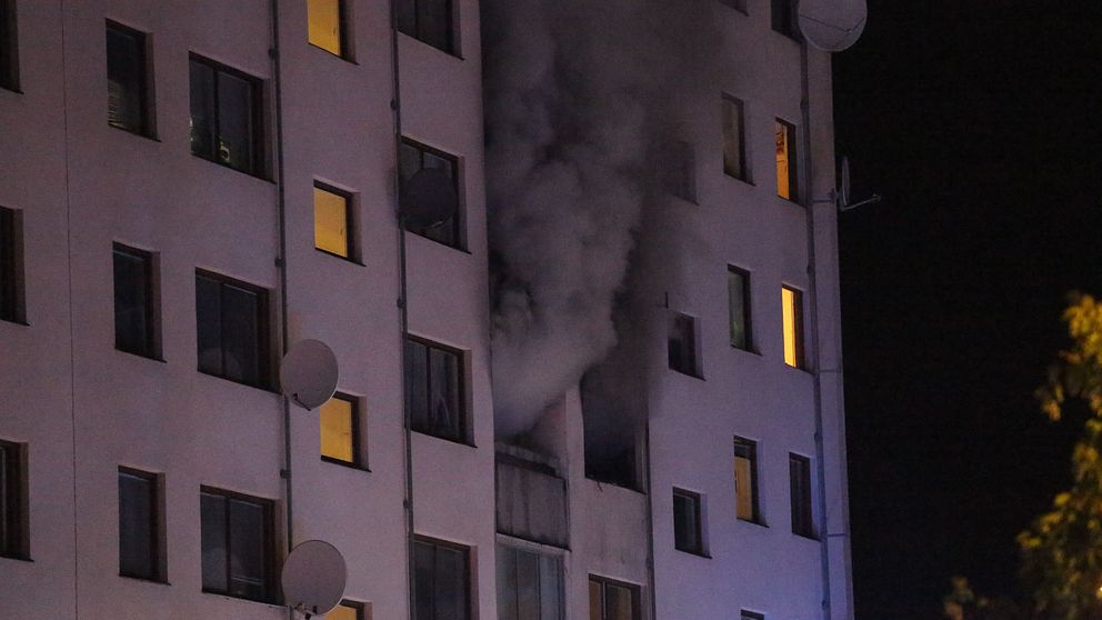Det brinner på fjärde våningen i ett lägenhetshus i Bredäng, Stockholm på söndagsmorgonen. Rök stiger upp ur fönster.