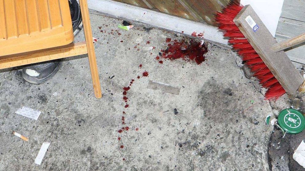 blodfläckar på ett betonggolv vid en ytterdörr.