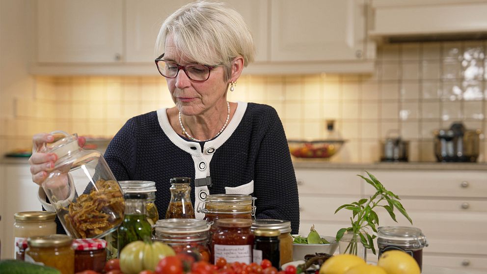 Livsmedelsverkets mikrobiolog Åsa Rosengren står vid ett bord med grönsaker i glasburkar.