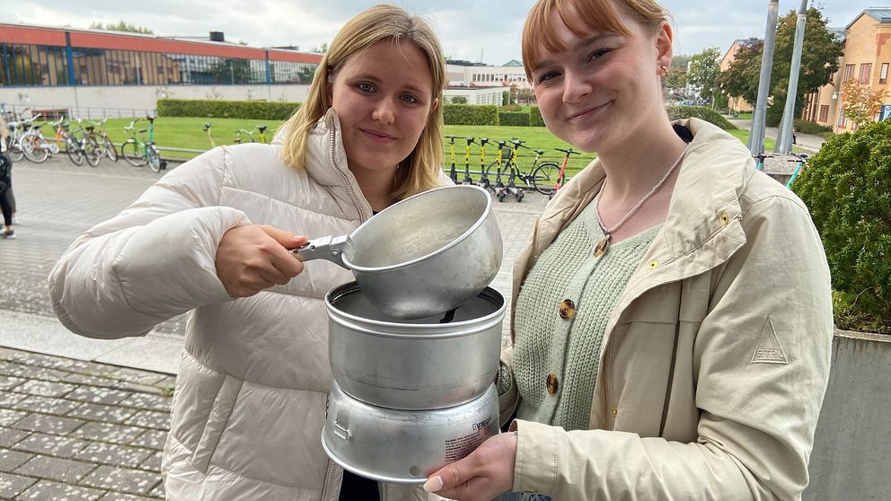 De blivande teaterpedagogerna Tilde Appelqvist och Hanna Hårstad Henriksson håller upp ett ihopsatt spritkök.