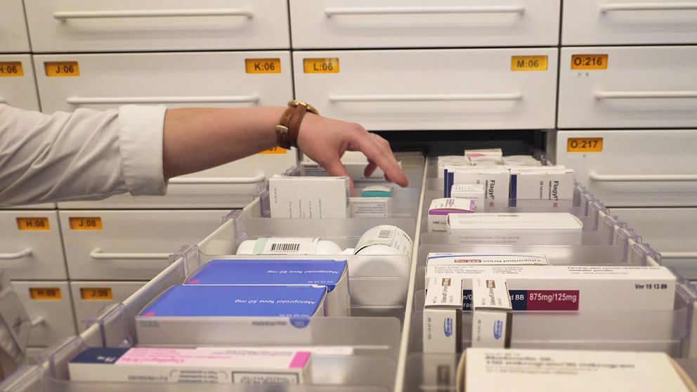 läkemedel och mediciner i en låda på apoteket, hand som lyfter upp en burk