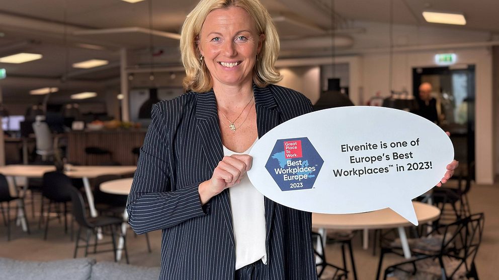 Leende kvinna håller upp skylt med prisutmärkelse