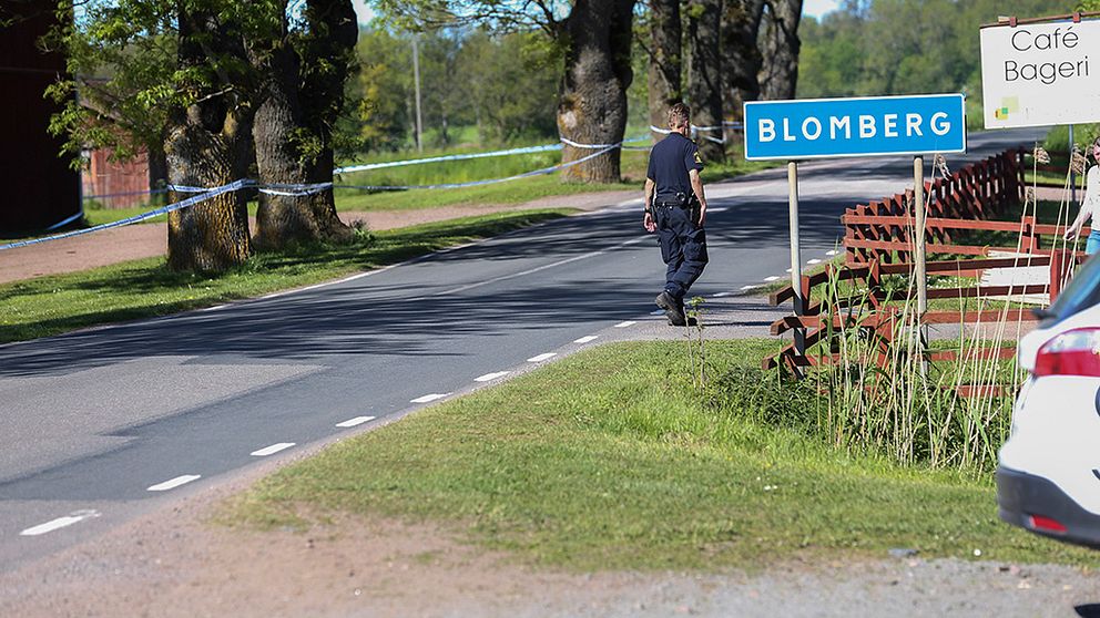 Bild av polis som går med ryggen till vid en skylt med ortsnamnet Blomberg på.