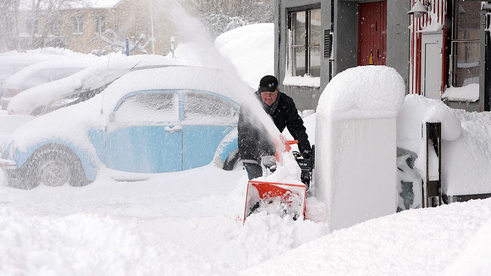Arkivbild. En man använder snöslunga för att gräva fram sin bil efter ett snöoväder i norra Uppland.