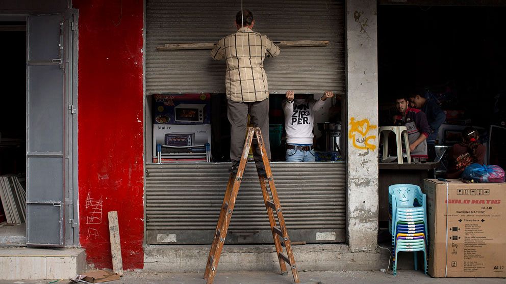En palestinsk man reparerar sin affär som skadats i den senaste tidens strider.