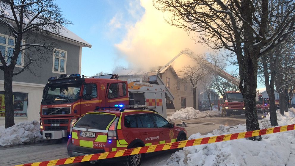 Brandbilar och ett hus med en rökpelare från det delvis inrasade taket.