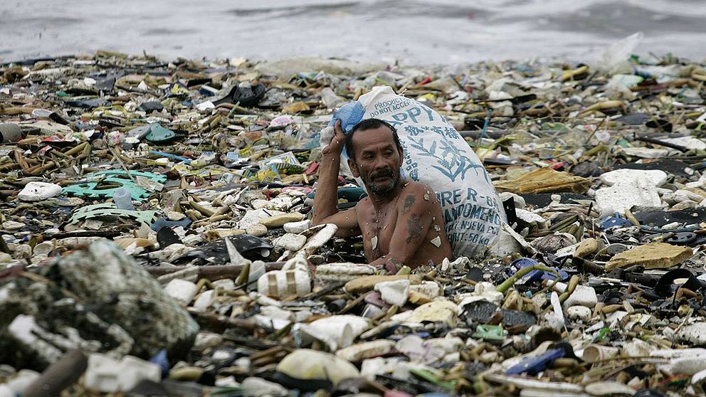 En filipinsk man samlar plast som drivit i land.