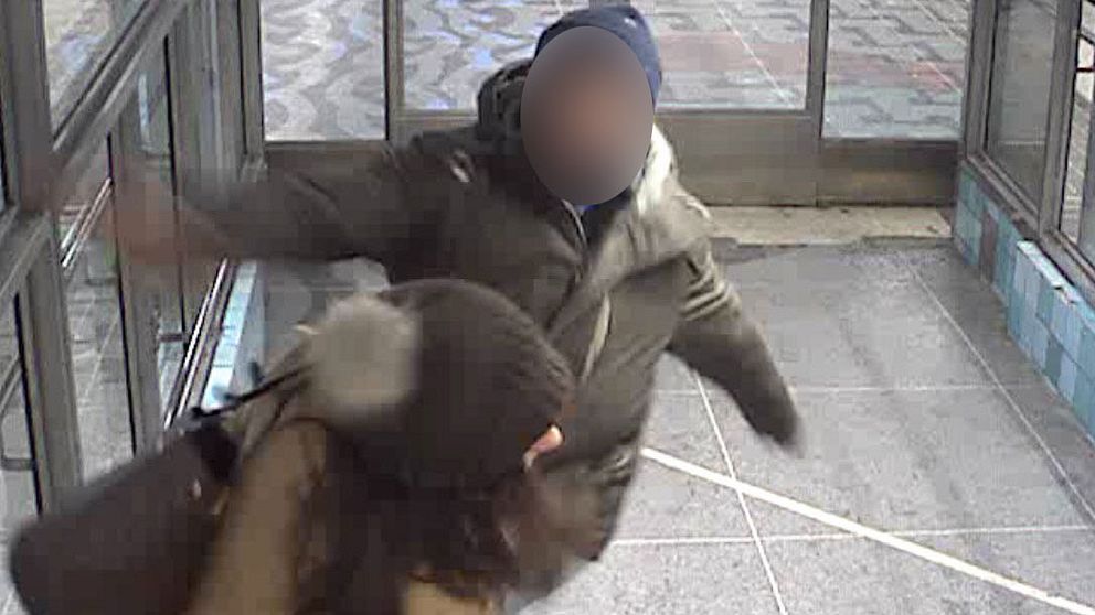 Mannen slår kvinnan i ansiktet med knuten näve medan hon skyddar barnen.