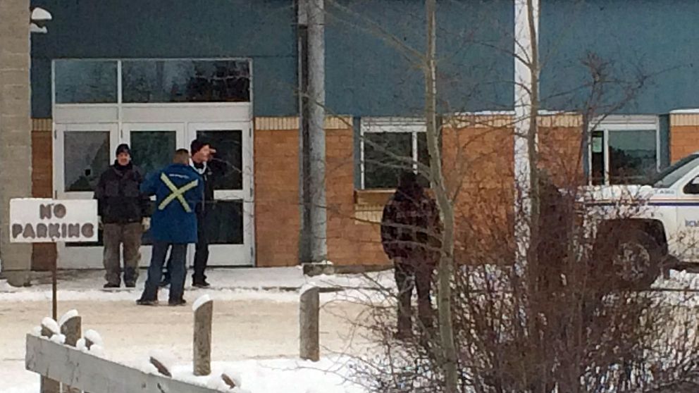 Personer står utanför La Loche Community School i Kanada.