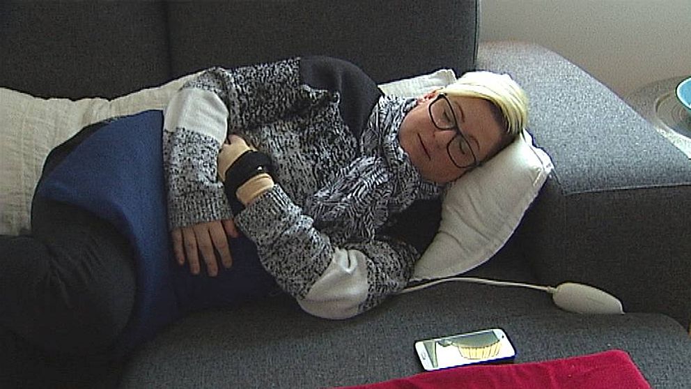 Sarah Nilsson har en allvarlig form av endometrios, med svåra smärtor som följd. Hon ligger på soffan med sin värmedyna på magen, för att få lite lindring.