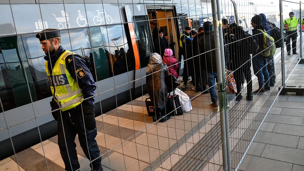 Flyktingar kliver av tåget bakom det nya staketet efter id-kontroller i Malmö.