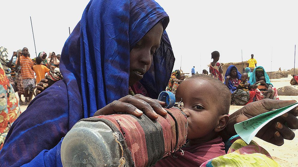 En kvinna ger sitt undernärda barn vatten ur en flaska.