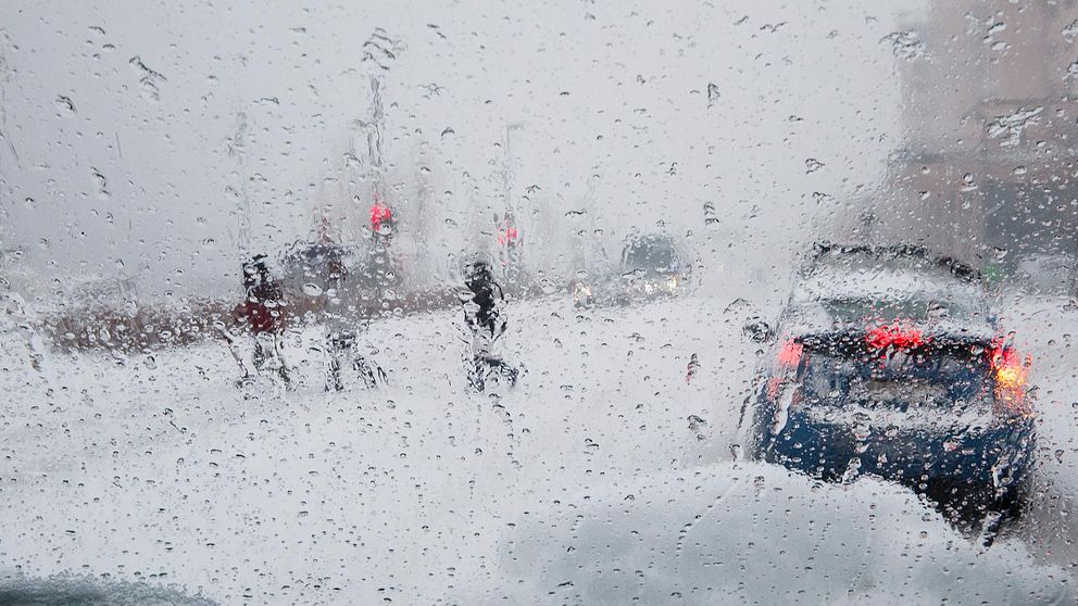 Inifrån en bil med snö och vatten på rutan. Vinterväder utanför.