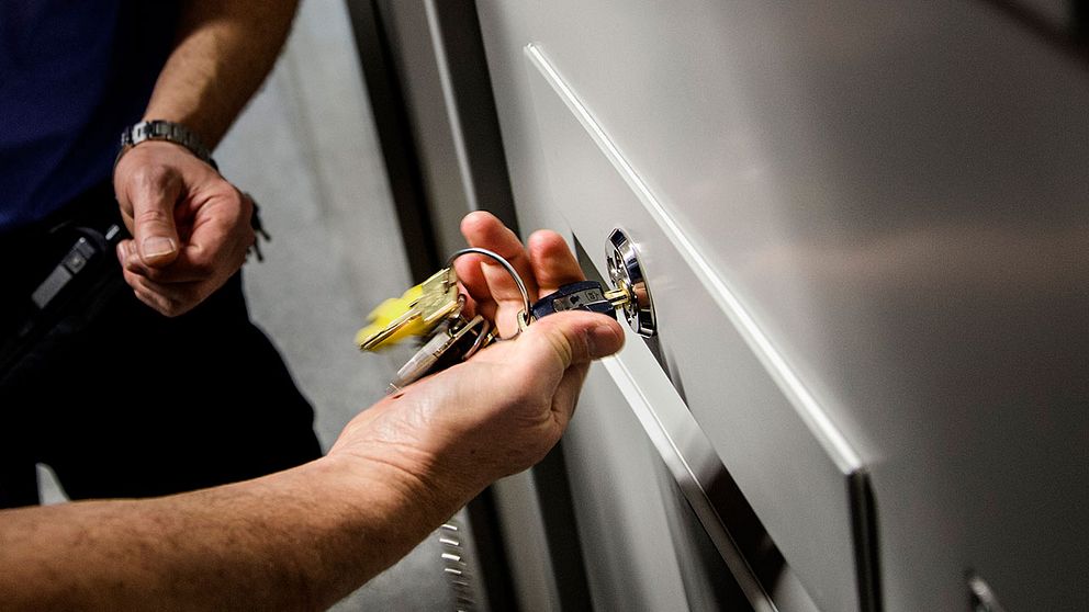 En häktesvakt använder nycklar för att öppna en celldörr.