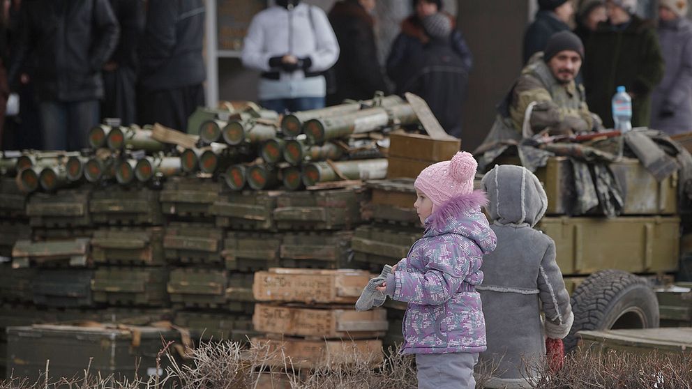 Barn väntar på leverans av förnödenheter framför en vapenansamling i Debaltseve i östra Ukraina, nordöst om Donetsk.