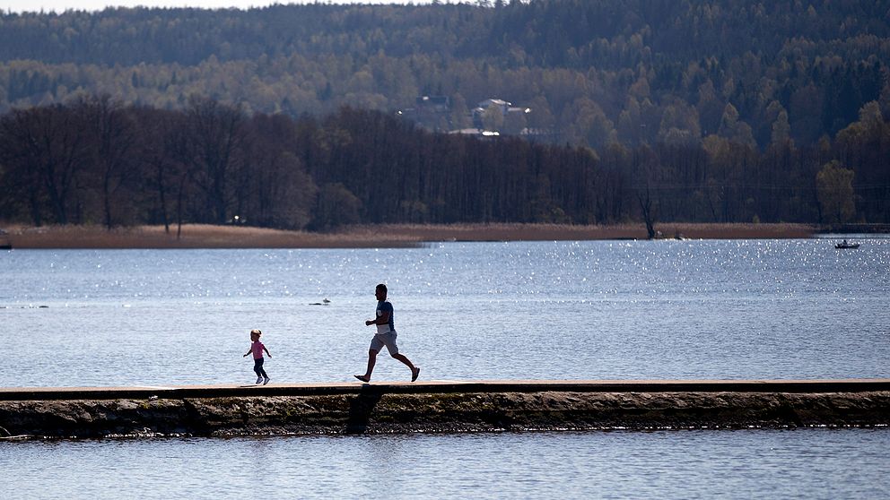 En man och ett barn njuter av vårvädret vid Aspens badplats i Lerum.
