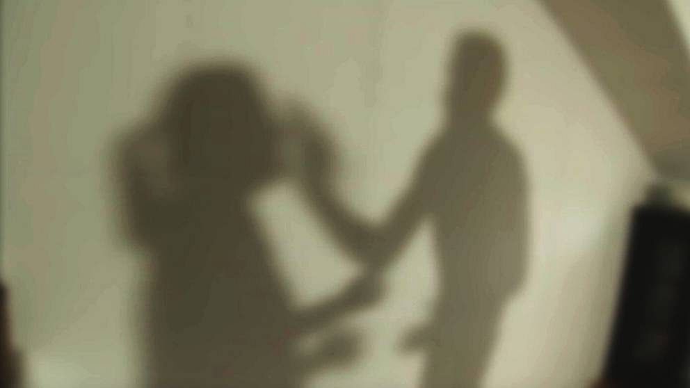 En anonym skuggbild med en man som slår en kvinna.