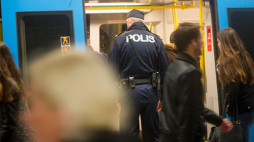 En polis står i en tunnelbanevagn.