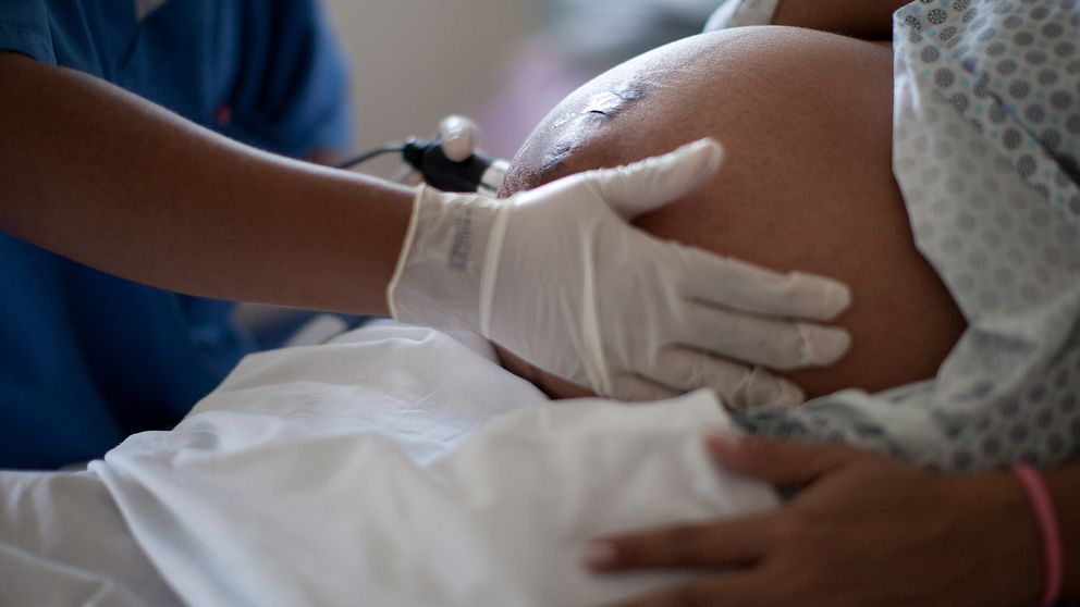 Gravid kvinna på sjukhus. Hennes mage undersöks av läkare.