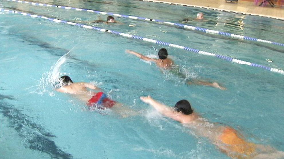 Elever tränar simning i bassängen.