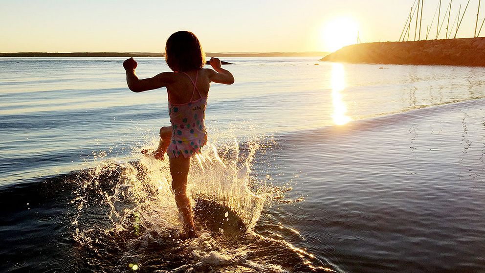 Ett barn hoppar i strandbrynet.