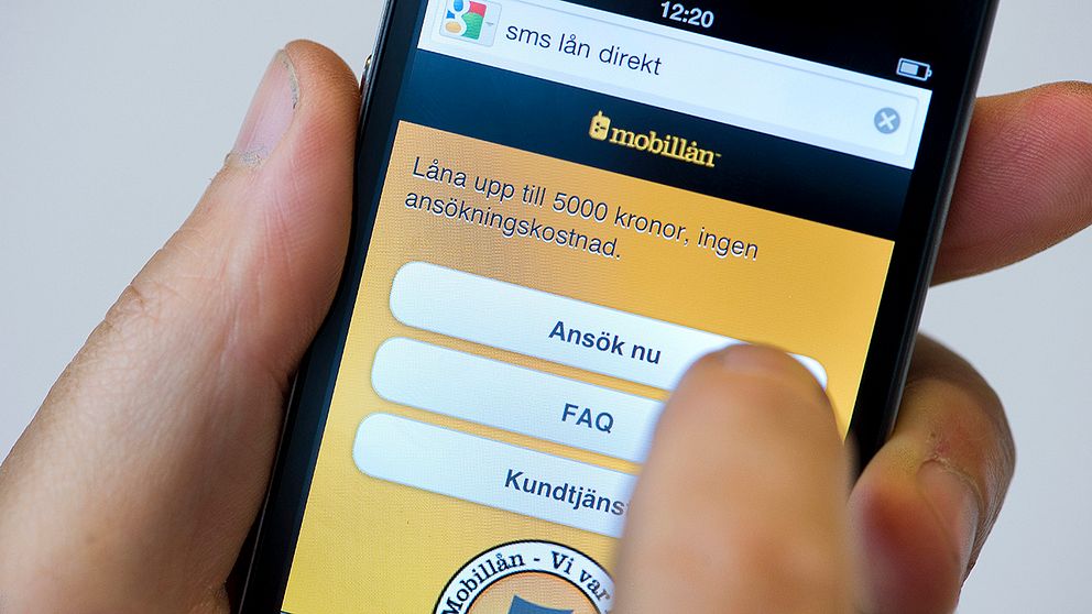 En person håller på att ta ett sms-lån med hjälp av sin mobiltelefon.