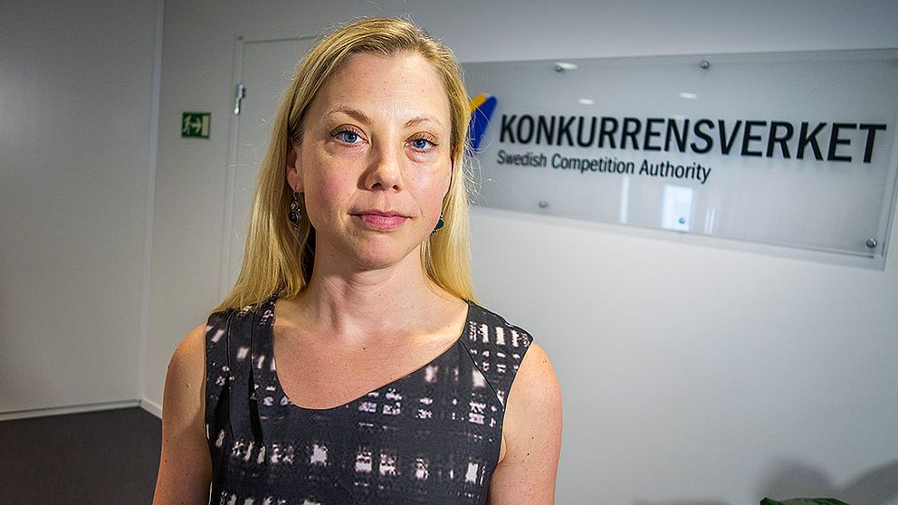 Blond kvinna tittar in i kameran. I bakgrunden syns skylt med texten ”Konkurrensverket”.