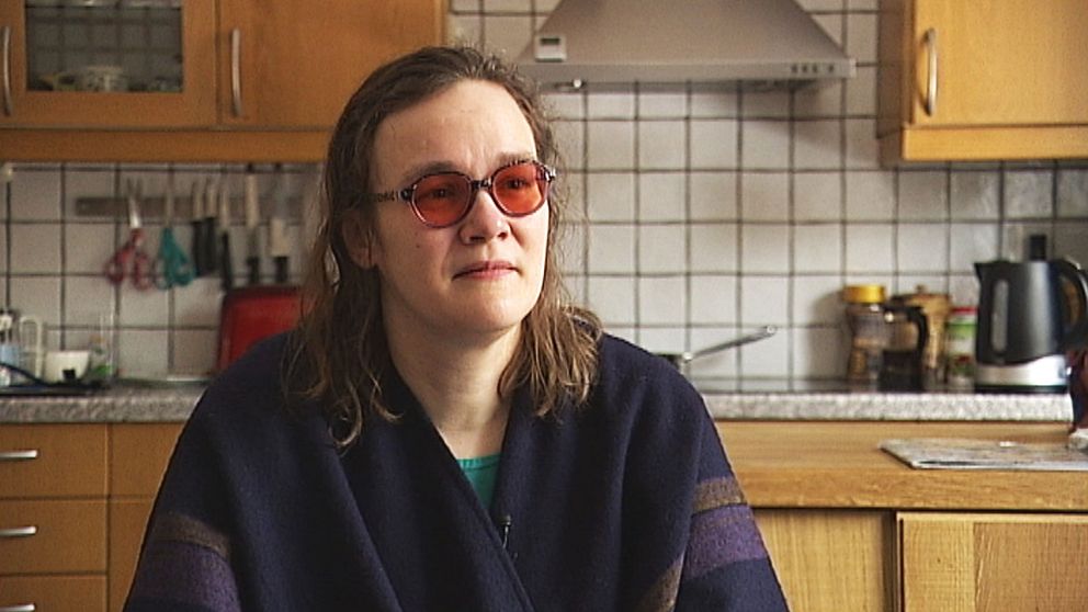 En kvinna med mörkt hår med röda solbrillor på i sitt kök.