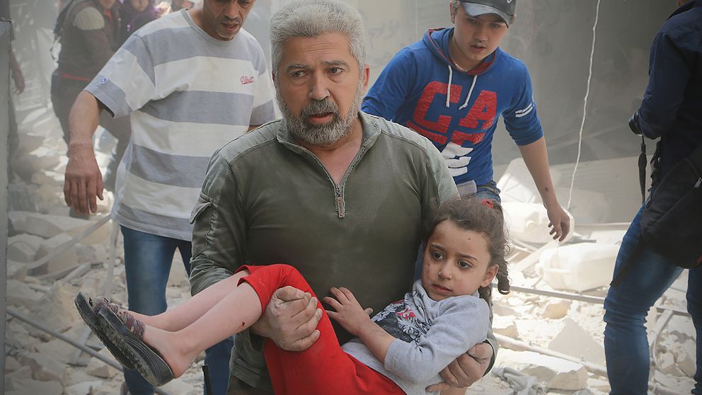 En man bär en skadad flicka efter ett bombangrepp mot Aleppo.