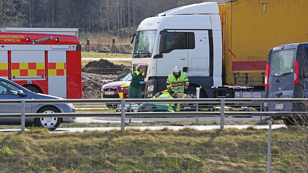 Brandbil, ambulans och personer som står böjda över en bår.