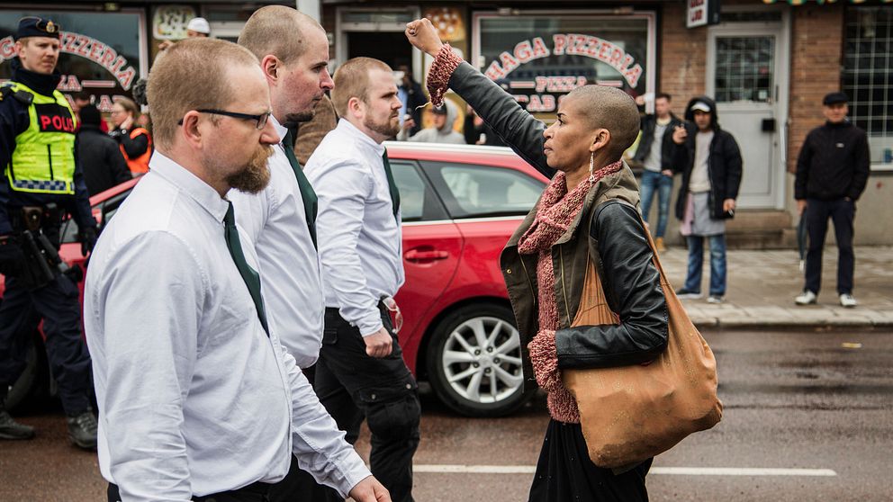Kvinna står med uppsträckt arm framför första Nordiska Motståndsrörelsen, under första maj i Borlänge 2016.